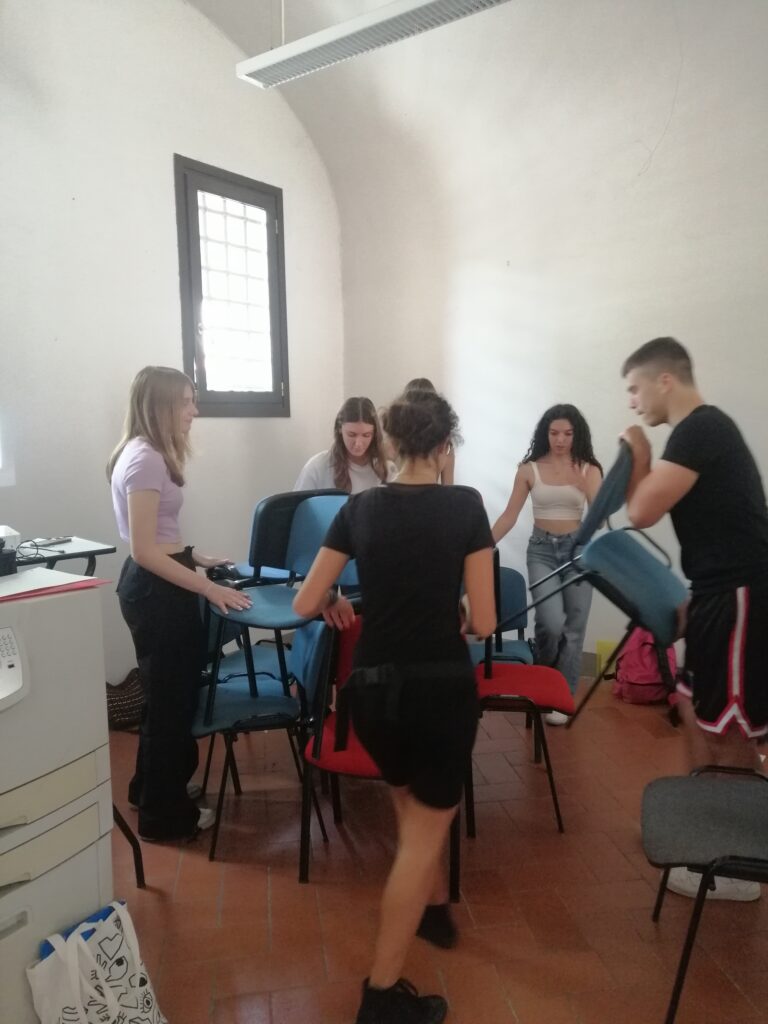 I ragazzi e le ragazze di EUKEYS al lavoro: preparano la sala dell'Ufficio Sostenibilità di via dell'Agnolo 1/D di Firenze disponendo sedie e materiali al meglio